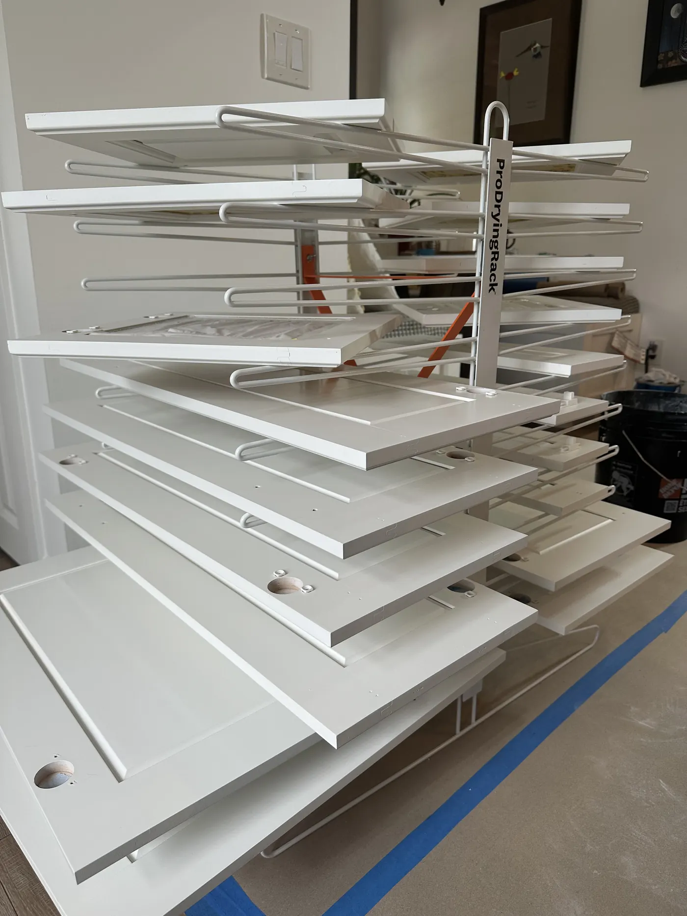 Cabinet doors hung on racks inside the sealed plastic-sheeted spray booth All In One Painting built in a client's garage